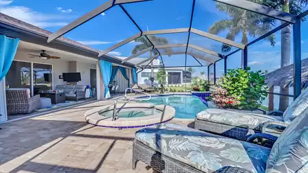 Covered patio featuring a cozy lounge, dining table, and view of the pool with spa.