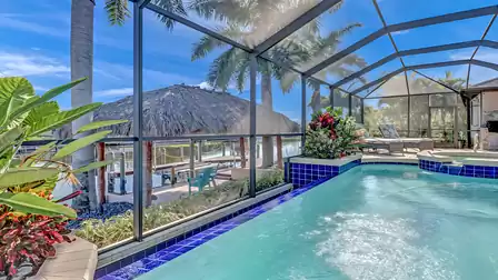 Heated pool with waterfall, overlooking the canal and the large tiki hut by the boat dock.