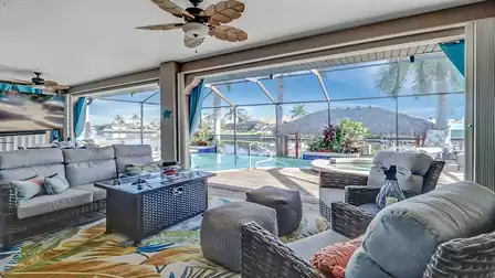 Covered lanai area with cozy lounge furniture and direct view of the pool and canal.