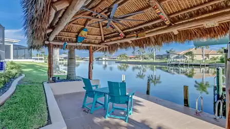 Cozy seating area under the large tiki roof overlooking the wide canal - the perfect spot to relax.