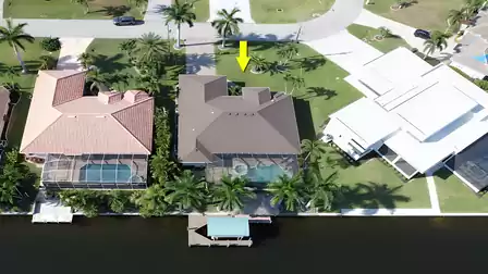 Aerial view of the vacation home with marked location, tropical landscaping, and direct canal access.