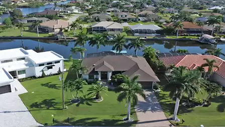 Aerial view of the well-maintained villa with pool area, tropical landscaping, and direct canal access.