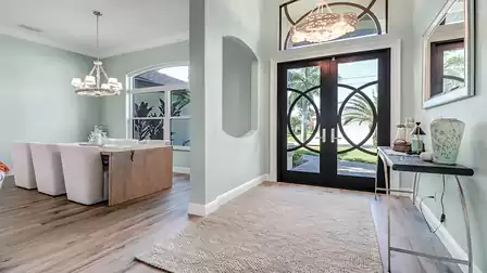 Welcoming entrance area with distinctive double doors, light-colored walls, and an elegant chandelier.