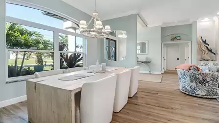Open dining area featuring a large wooden table, six upholstered chairs, and a view into the living room.