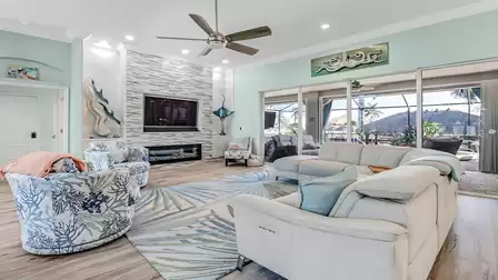 Spacious living room with modern design, cozy sectional sofa, and large TV, offering a direct view of the pool area.