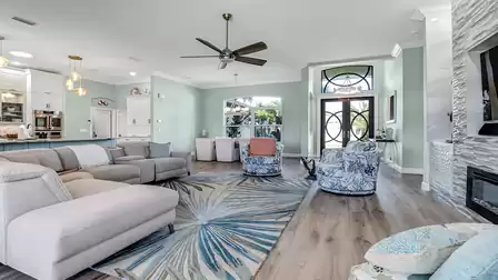Open-concept living space with a large sectional sofa, dining area, and views of the entryway and kitchen.