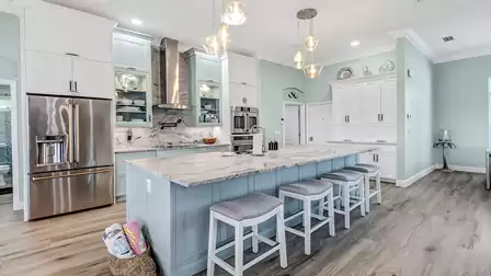 Modern kitchen with large island, four barstools, and elegant granite countertop