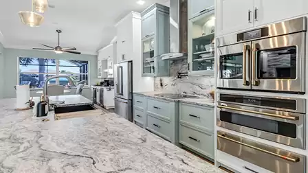 View of open kitchen with large fridge, cooktop, double oven, and window overlooking the canal