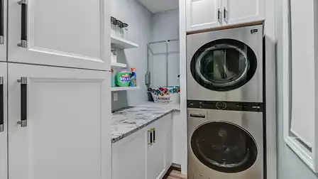 Laundry room with modern LG washer and dryer, white cabinets, and granite countertop