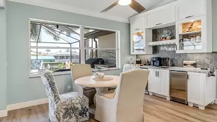 Cozy seating corner with mixed chairs, coffee bar, sink, wine glass rack, and built-in beverage fridge - overlooking the canal.