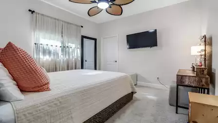 Guest bedroom with cozy bed, wall-mounted TV, and rustic-style vanity table.
