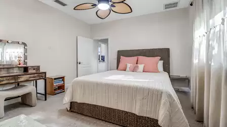 Bright bedroom with woven bed frame, decorative pillows, and vanity - ideal for children or guests.