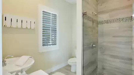 Bright bathroom with a glass shower, elegant tiles, and stylish wall decor.