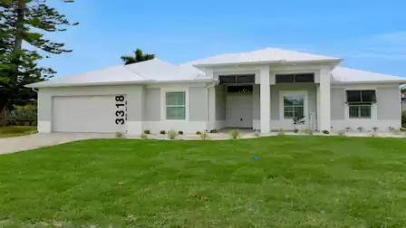 Modern, single-story Villa Cupido in Cape Coral with a white facade, well-maintained lawn, and covered entrance area.