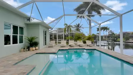 Luxurious pool area of Villa Cupido with shimmering water, covered patio, and scenic canal views.