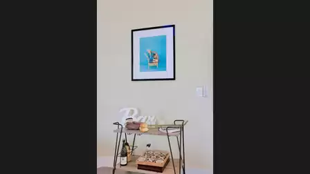 Stylish bar corner with a decorative serving cart, wall art, and a small selection of drinks.