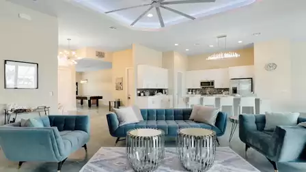 Open living area with modern blue sofas, a high ceiling with LED lighting, and direct connection to the kitchen.