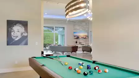 Billiard table in the recreation area with a view of the living room and an Einstein portrait on the wall.