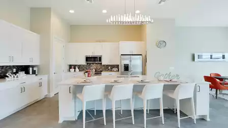 Modern open kitchen with white cabinets, island with barstools, and stylish lighting.
