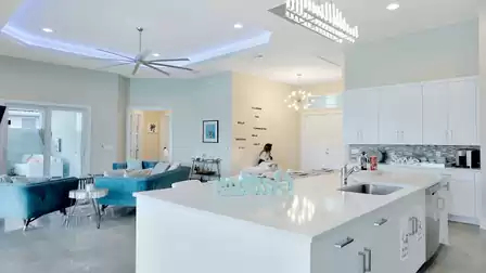 White kitchen island with modern decor and adjacent living area with designer furniture.