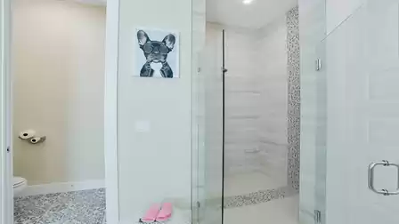 Spacious walk-in shower with glass partition and wall art.