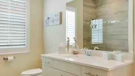 Modern bathroom with a large mirror, sink, and decorative elements.