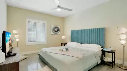 Cozy bedroom with a turquoise headboard, modern lamps, and a TV.