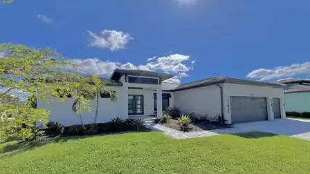 Modern vacation villa in Cape Coral with manicured front yard, bright facade, and spacious driveway leading to the garage