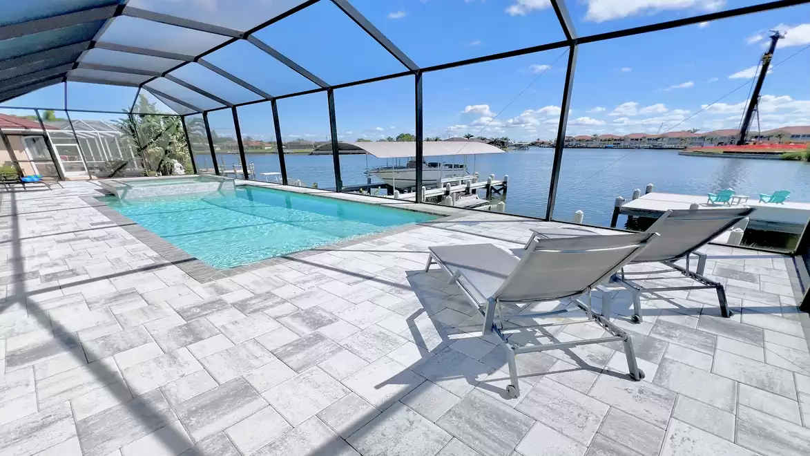 View from the screened terrace of Villa Aldiana in Cape Coral showing the pool, spa, and wide canal with boat dock