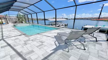 View from the screened terrace of Villa Aldiana in Cape Coral showing the pool, spa, and wide canal with boat dock