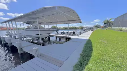 Covered boat dock with boat and well-kept lawn area by the canal.
