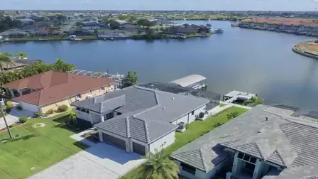Rear view of the house with covered boat lift and spacious screened-in area by the water.