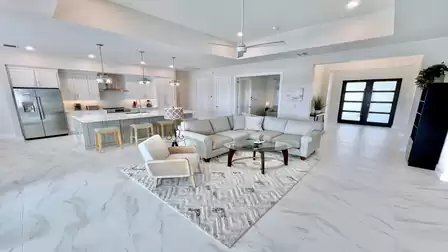 Spacious living area with modern kitchen, island, and comfortable sofa corner.