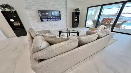 Living area with cozy sectional sofa, TV wall and direct access to the patio.