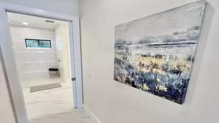 The hallway from the bedroom to the bathroom is bright and tastefully designed - the modern artwork adds an elegant touch.