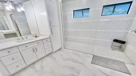 The primary bathroom features an oversized walk-in shower and a sleek vanity with ample storage space.