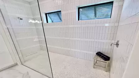 The walk-in shower features dual shower heads and natural light from two windows for a spa-like experience.