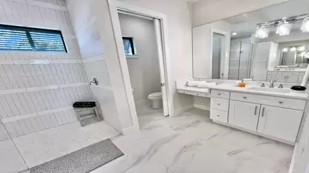 The bright master bathroom offers a walk-in shower, a separate toilet room, and a spacious vanity with a dedicated makeup area.