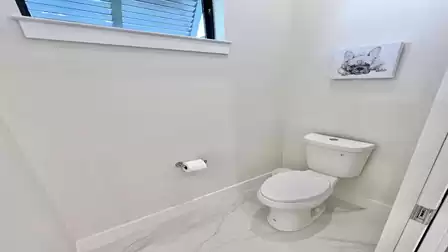 The separate toilet room in the master bathroom ensures privacy and is tastefully decorated with a window and charming accents.