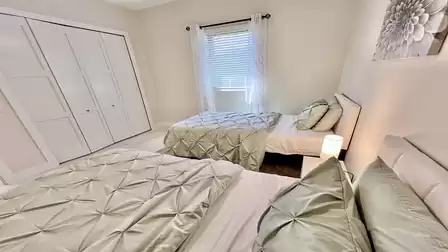 Guest Bedroom 3 features two twin beds with coordinated bedding for a cozy and stylish feel. Large windows with sheer curtains provide natural light, and a spacious built-in closet offers ample storage space.