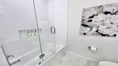 Guest bathroom with bathtub and modern glass enclosure.
