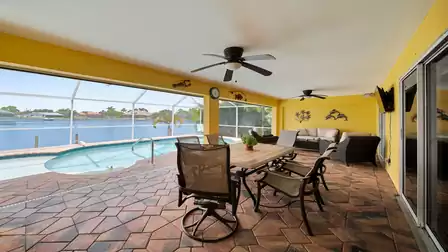 Covered terrace with dining table, lounge furniture and ceiling fans - direct view of the pool and the sparkling waters of the lake