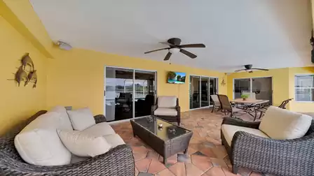 Comfortable lounge furniture on the covered terrace with ceiling fan, TV - stylish outdoor living area to relax in.