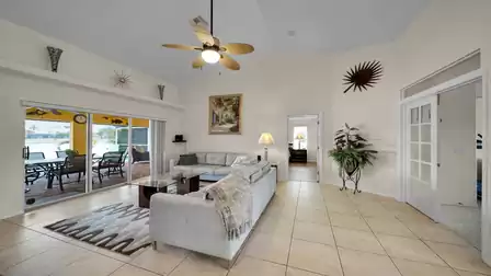 Bright living room with comfortable sofas and a direct view of the terrace and lake through large sliding glass doors.