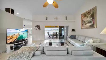 Modern living room with large leather sofa, flat-screen TV, and direct access to the covered terrace with lake view.
