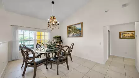 Elegant dining area with round glass table, comfortable chairs, and large window letting in natural light – a stylish setting for shared meals.