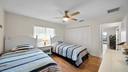 Bright guest room with two twin beds, ceiling fan and walk-in closet