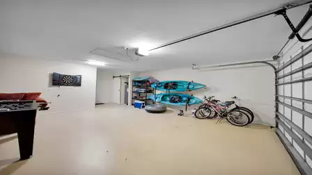 Spacious garage with two kayaks, bicycles, shelving, dartboard, and foosball table – perfect for active vacationers.