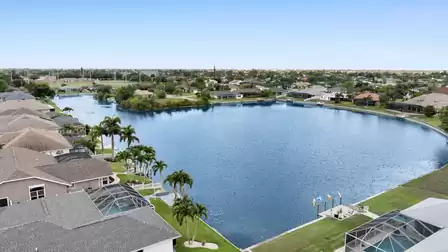 Aerial view of the picturesque lake with well-kept gardens and palm trees – peaceful, green neighborhood right by the water.