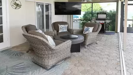 Comfortable chairs, a stylish fire table and a TV view create a welcoming outdoor lounge.